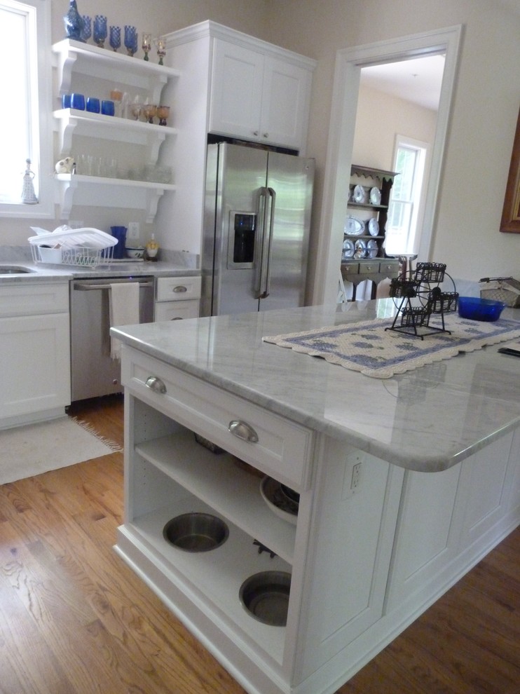Inredning av ett medelhavsstil avskilt, mellanstort u-kök, med en undermonterad diskho, luckor med infälld panel, vita skåp, marmorbänkskiva, rostfria vitvaror, ljust trägolv, en köksö och beiget golv