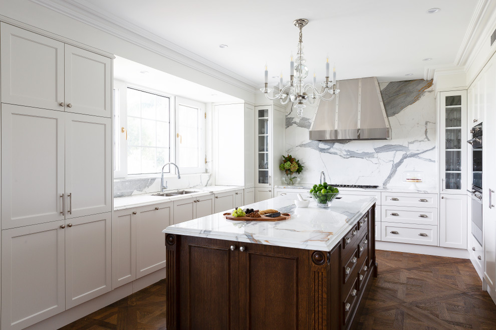 Idéer för ett avskilt klassiskt vit u-kök, med en dubbel diskho, luckor med infälld panel, vita skåp, marmorbänkskiva, flerfärgad stänkskydd, stänkskydd i marmor, rostfria vitvaror, mellanmörkt trägolv, en köksö och brunt golv