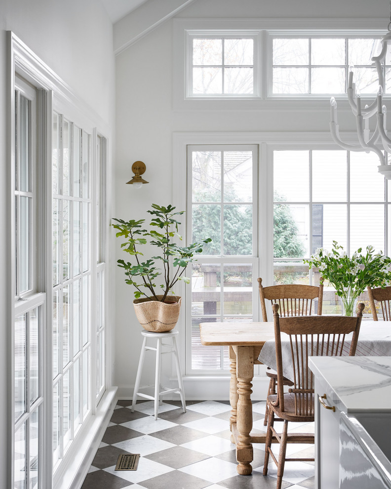 Lantlig inredning av ett stort vit vitt kök, med en rustik diskho, skåp i shakerstil, grå skåp, vitt stänkskydd, stänkskydd i terrakottakakel, rostfria vitvaror, marmorgolv, en köksö och flerfärgat golv