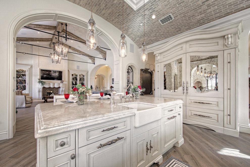 Inspiration for a huge u-shaped medium tone wood floor and brown floor enclosed kitchen remodel in Phoenix with recessed-panel cabinets, light wood cabinets, two islands, a farmhouse sink, marble countertops, white backsplash, terra-cotta backsplash, paneled appliances and multicolored countertops