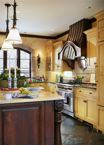 Klassisk inredning av ett mellanstort kök, med en rustik diskho, luckor med profilerade fronter, gula skåp, bänkskiva i täljsten, gult stänkskydd, stänkskydd i mosaik, rostfria vitvaror, skiffergolv, en köksö och brunt golv