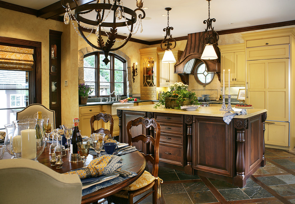 Bild på ett mellanstort vintage kök, med en rustik diskho, luckor med profilerade fronter, gula skåp, bänkskiva i täljsten, gult stänkskydd, stänkskydd i mosaik, integrerade vitvaror, skiffergolv, en köksö och brunt golv
