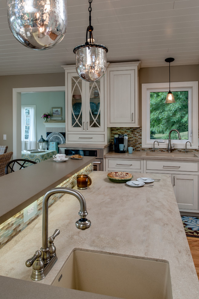 Eat-in kitchen - mid-sized traditional l-shaped medium tone wood floor eat-in kitchen idea in Other with an integrated sink, recessed-panel cabinets, gray cabinets, solid surface countertops, multicolored backsplash, glass sheet backsplash, stainless steel appliances and an island