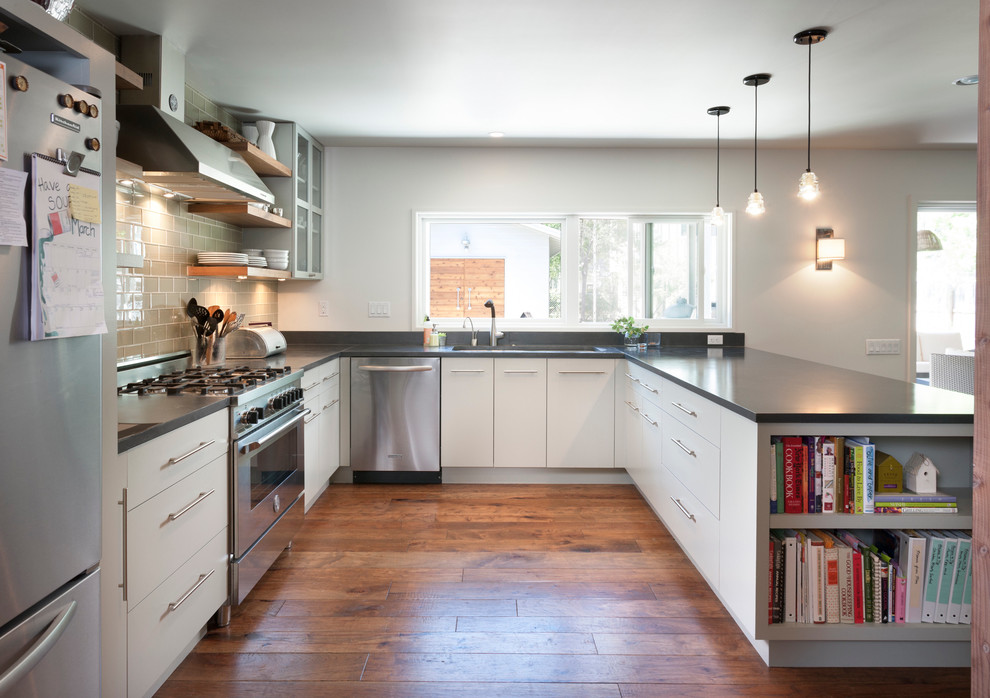 Diseño de cocinas en U actual con armarios con paneles lisos, electrodomésticos de acero inoxidable y salpicadero de azulejos tipo metro