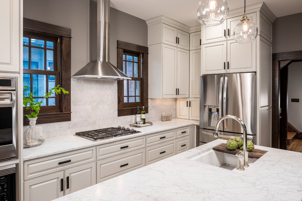 Inspiration for a timeless light wood floor kitchen remodel in Minneapolis with beaded inset cabinets, white cabinets, marble countertops, white backsplash, glass tile backsplash, stainless steel appliances, an island and an undermount sink