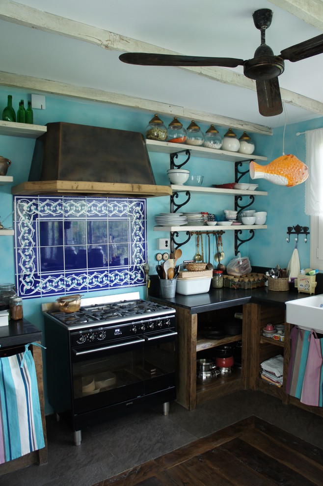 This is an example of an eclectic kitchen in London with open cabinets, blue splashback and black appliances.