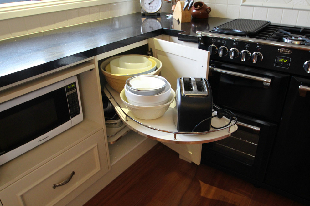 Eat-in kitchen - large cottage l-shaped medium tone wood floor eat-in kitchen idea in Melbourne with a drop-in sink, beaded inset cabinets, beige cabinets, quartz countertops, beige backsplash, ceramic backsplash, black appliances and an island