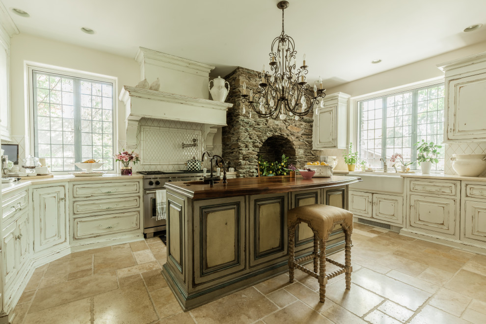 This is an example of a vintage u-shaped kitchen in New York with raised-panel cabinets, white splashback, stainless steel appliances, an island, beige floors, beige worktops and distressed cabinets.