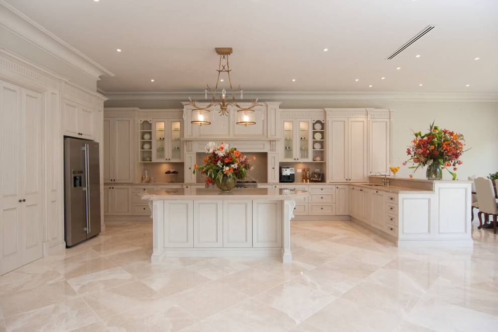 Exempel på ett mycket stort lantligt kök, med en undermonterad diskho, luckor med profilerade fronter, skåp i ljust trä, marmorbänkskiva, beige stänkskydd, stänkskydd i marmor, rostfria vitvaror, marmorgolv, en köksö och beiget golv