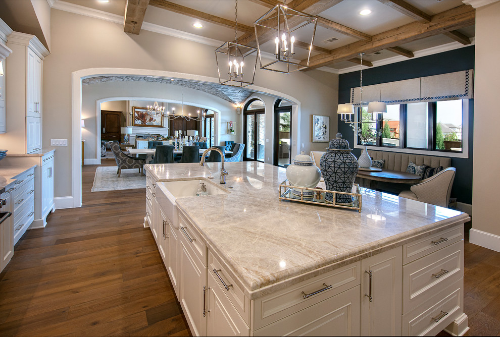 Photo of a large traditional galley kitchen/diner in Dallas with a belfast sink, recessed-panel cabinets, white cabinets, engineered stone countertops, multi-coloured splashback, cement tile splashback, stainless steel appliances, medium hardwood flooring, an island and beige worktops.