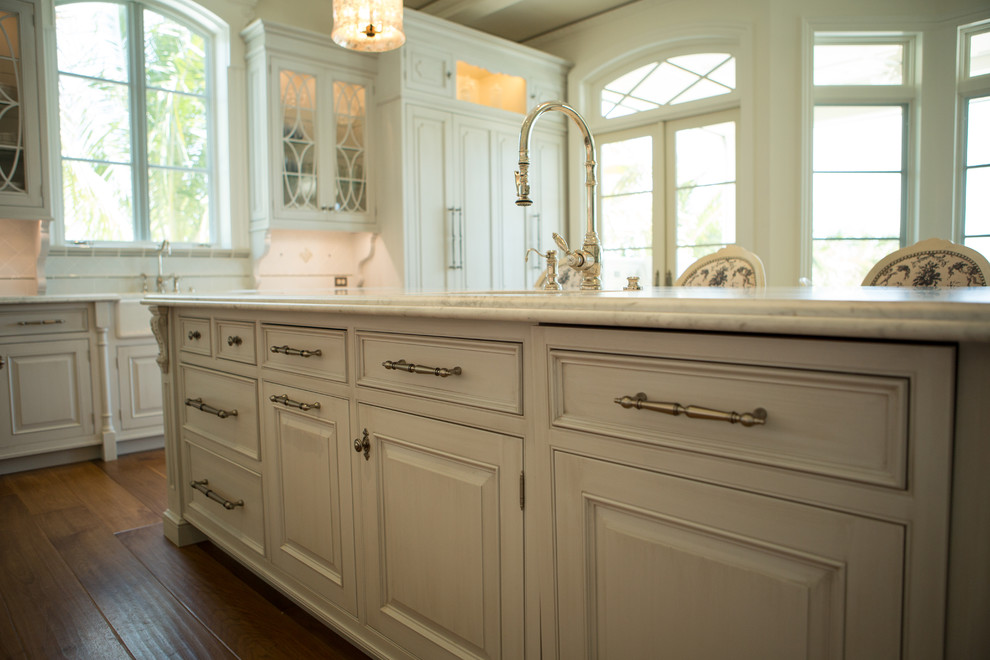 Klassisk inredning av ett mycket stort kök, med en rustik diskho, marmorbänkskiva, vitt stänkskydd, stänkskydd i stenkakel, integrerade vitvaror, mellanmörkt trägolv och en köksö