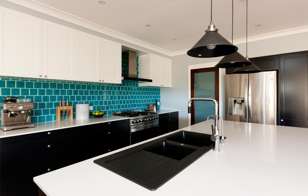 Inspiration for a medium sized modern l-shaped open plan kitchen in Sydney with a double-bowl sink, shaker cabinets, black cabinets, engineered stone countertops, metro tiled splashback, stainless steel appliances, an island, white worktops, blue splashback, beige floors and porcelain flooring.
