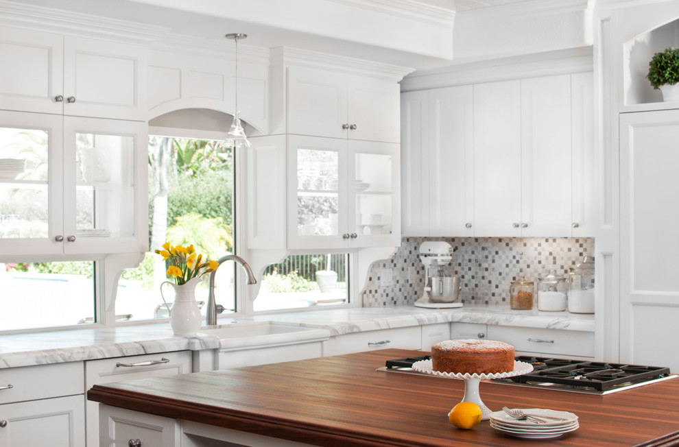 Example of a large classic u-shaped dark wood floor open concept kitchen design in San Diego with a farmhouse sink, shaker cabinets, white cabinets, wood countertops, gray backsplash, paneled appliances and an island