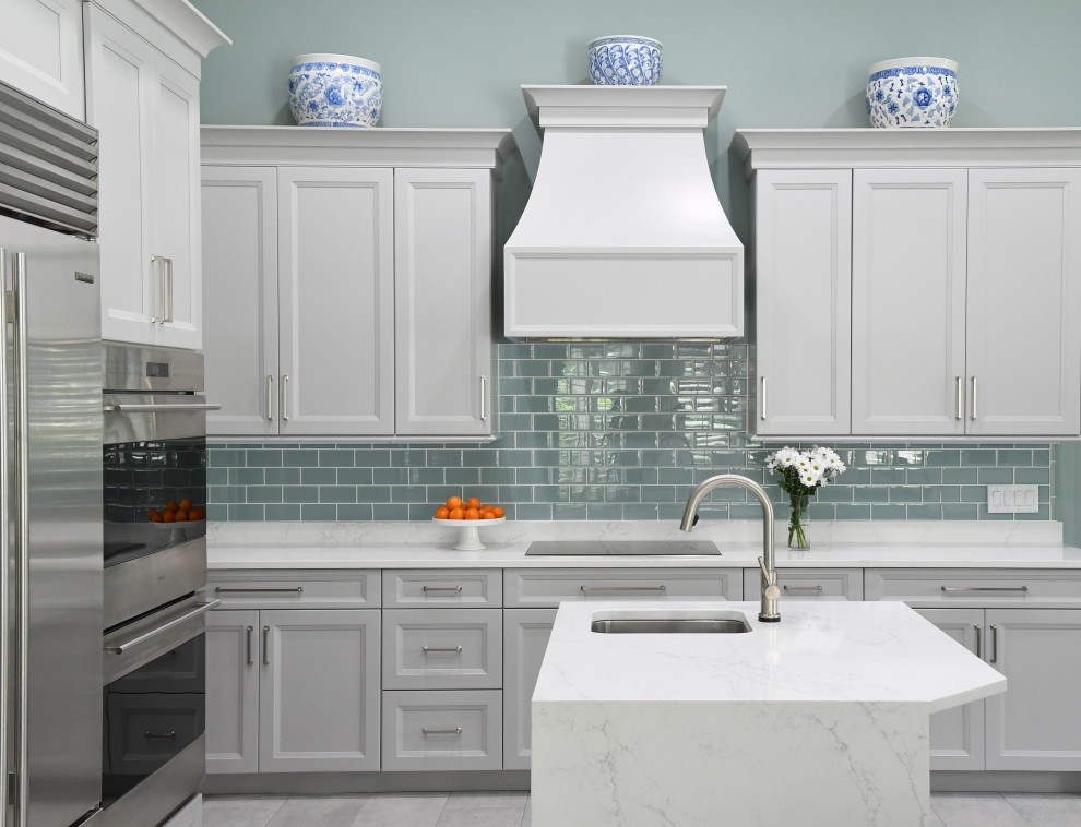 Klassisk inredning av ett mellanstort vit vitt kök, med en undermonterad diskho, grå skåp, bänkskiva i koppar, blått stänkskydd, stänkskydd i glaskakel, rostfria vitvaror, klinkergolv i porslin, flera köksöar och grått golv