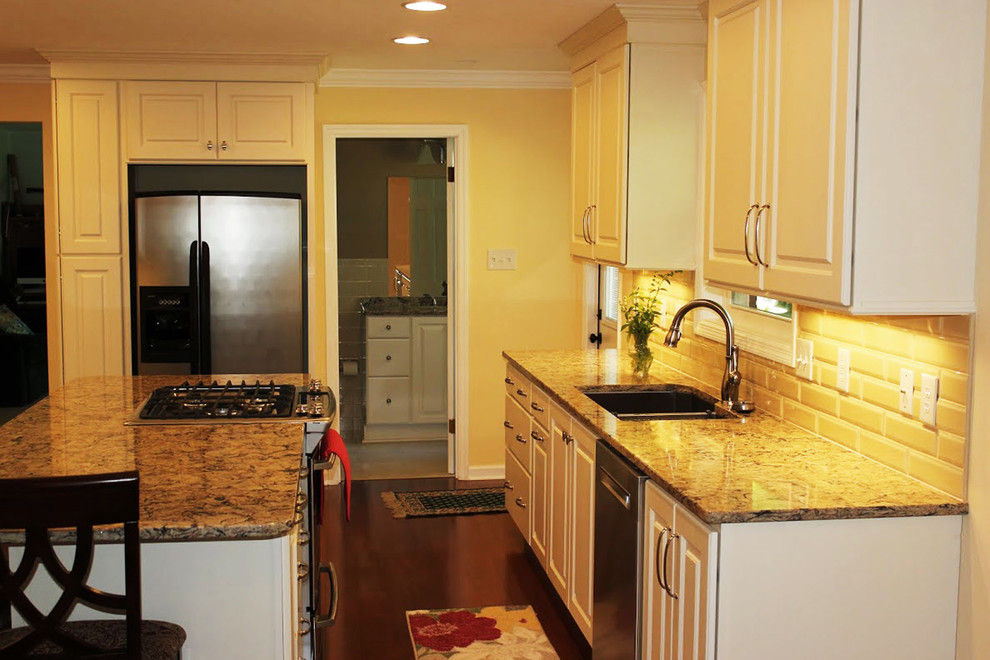 Bild på ett mellanstort vintage kök, med en dubbel diskho, luckor med infälld panel, vita skåp, granitbänkskiva, vitt stänkskydd, stänkskydd i keramik, rostfria vitvaror, mellanmörkt trägolv och en köksö