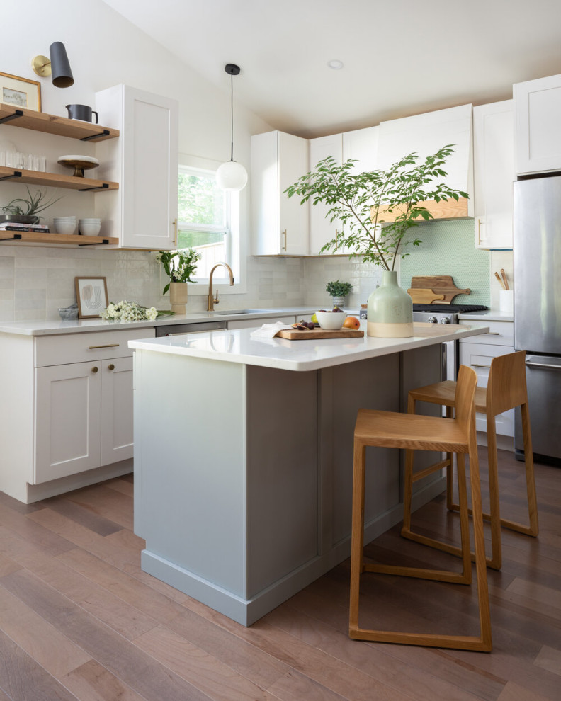 Classic l-shaped kitchen in DC Metro with a submerged sink, shaker cabinets, white cabinets, white splashback, stainless steel appliances, medium hardwood flooring, an island, brown floors, white worktops and a vaulted ceiling.
