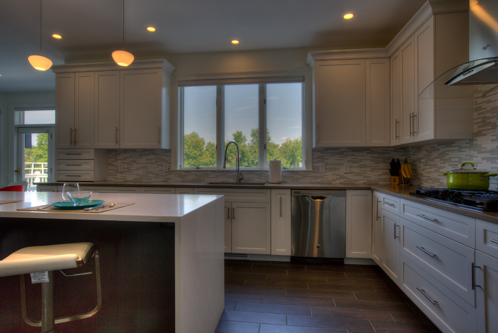 Photo of an expansive contemporary l-shaped open plan kitchen in Bridgeport with a submerged sink, shaker cabinets, white cabinets, engineered stone countertops, white splashback, mosaic tiled splashback, stainless steel appliances, porcelain flooring and an island.