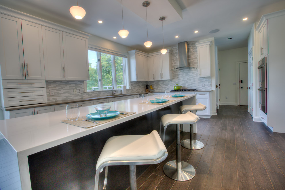 Design ideas for an expansive contemporary l-shaped open plan kitchen in Bridgeport with a submerged sink, shaker cabinets, white cabinets, engineered stone countertops, white splashback, mosaic tiled splashback, stainless steel appliances, porcelain flooring and an island.