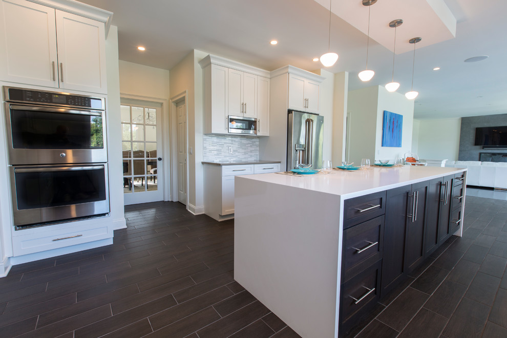 Photo of an expansive contemporary l-shaped open plan kitchen in Bridgeport with a submerged sink, shaker cabinets, white cabinets, engineered stone countertops, white splashback, mosaic tiled splashback, stainless steel appliances, porcelain flooring and an island.