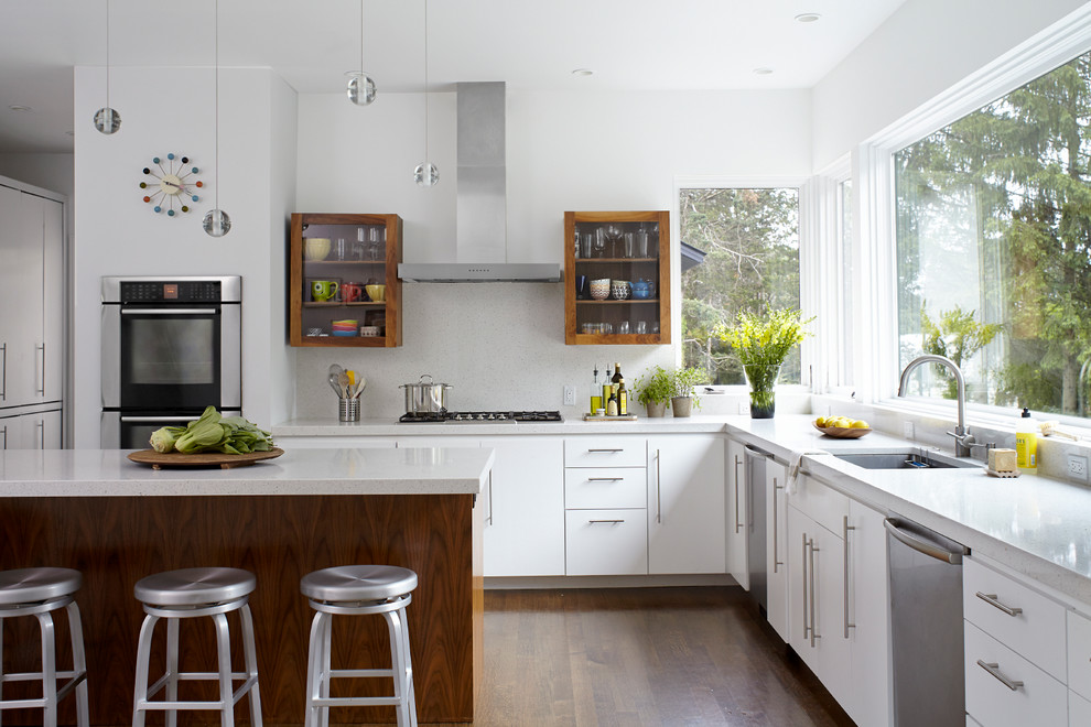 Moderne Küche in L-Form mit Unterbauwaschbecken, flächenbündigen Schrankfronten, weißen Schränken, Küchenrückwand in Weiß, Küchengeräten aus Edelstahl, dunklem Holzboden und Kücheninsel in New York