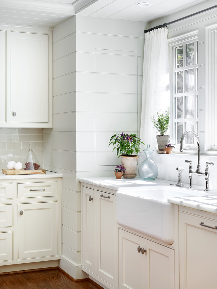 Inspiration for a mid-sized transitional u-shaped medium tone wood floor and brown floor enclosed kitchen remodel in Atlanta with a farmhouse sink, beaded inset cabinets, white cabinets, an island, gray backsplash, subway tile backsplash, stainless steel appliances and marble countertops