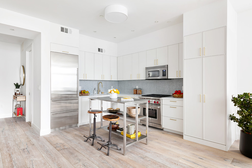 Moderne Küche in L-Form mit flächenbündigen Schrankfronten, weißen Schränken, Küchenrückwand in Blau, Küchengeräten aus Edelstahl, hellem Holzboden und Kücheninsel in New York