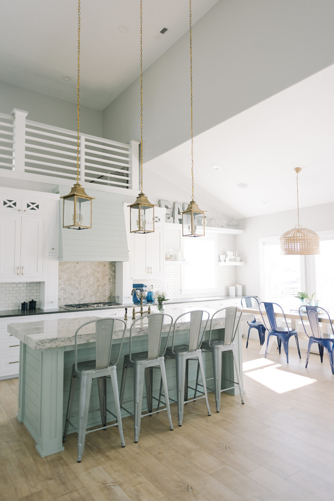 Large beach style light wood floor eat-in kitchen photo in Salt Lake City with an island, shaker cabinets, white cabinets, granite countertops, white backsplash, porcelain backsplash, stainless steel appliances and a farmhouse sink
