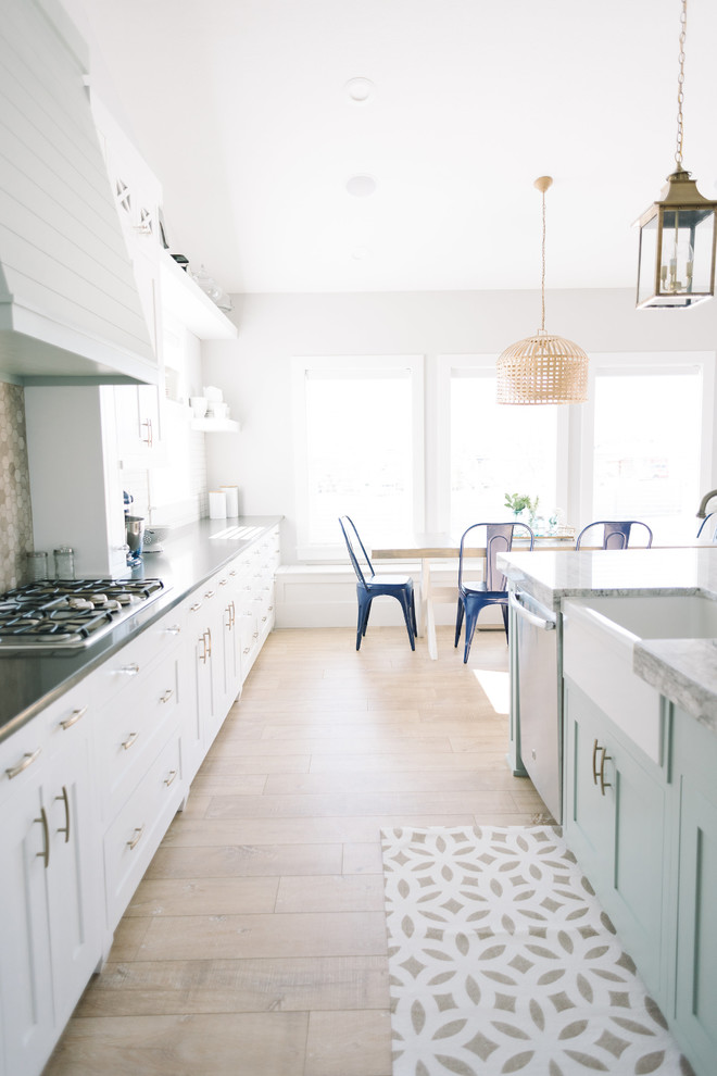 Eat-in kitchen - large coastal single-wall light wood floor eat-in kitchen idea in Salt Lake City with an island, shaker cabinets, white cabinets, quartz countertops, white backsplash, porcelain backsplash, stainless steel appliances and a farmhouse sink