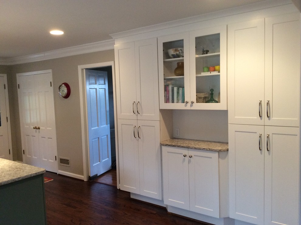 Mid-sized elegant l-shaped medium tone wood floor eat-in kitchen photo in Birmingham with an undermount sink, recessed-panel cabinets, white cabinets, granite countertops, white backsplash, ceramic backsplash and stainless steel appliances