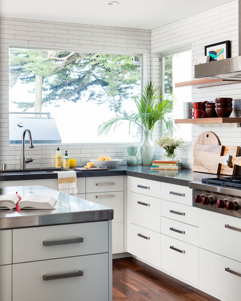 Photo of a contemporary l-shaped kitchen in San Francisco with a submerged sink, flat-panel cabinets, white cabinets, white splashback, stainless steel appliances, dark hardwood flooring and an island.