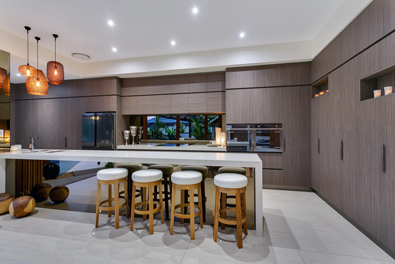 Foto på ett stort tropiskt kök, med en undermonterad diskho, bänkskiva i kvarts, stänkskydd med metallisk yta, glaspanel som stänkskydd, rostfria vitvaror, klinkergolv i porslin och en köksö