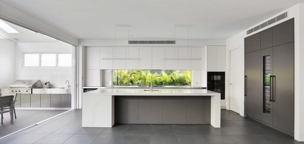 This is an example of a large modern l-shaped open plan kitchen in Sydney with a submerged sink, flat-panel cabinets, grey cabinets, engineered stone countertops, white splashback, window splashback, black appliances, porcelain flooring, an island, grey floors and white worktops.