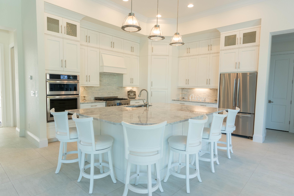 Large transitional l-shaped ceramic tile open concept kitchen photo in Miami with an undermount sink, shaker cabinets, white cabinets, granite countertops, gray backsplash, stone tile backsplash, stainless steel appliances and an island