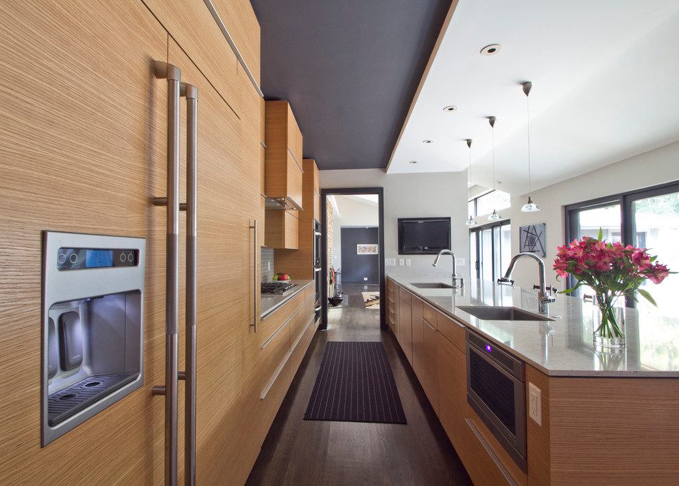 This is an example of a large modern galley kitchen/diner in Atlanta with a single-bowl sink, flat-panel cabinets, medium wood cabinets, granite worktops, grey splashback, ceramic splashback, integrated appliances, medium hardwood flooring, a breakfast bar and brown floors.