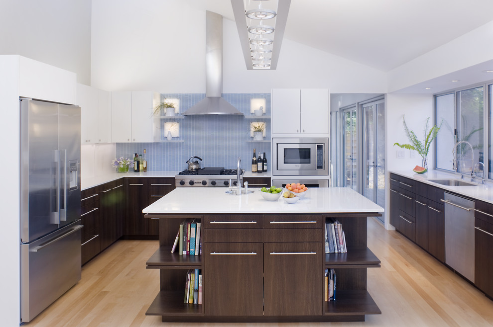 Пример оригинального дизайна: п-образная кухня в современном стиле с техникой из нержавеющей стали, врезной мойкой, плоскими фасадами, темными деревянными фасадами и синим фартуком