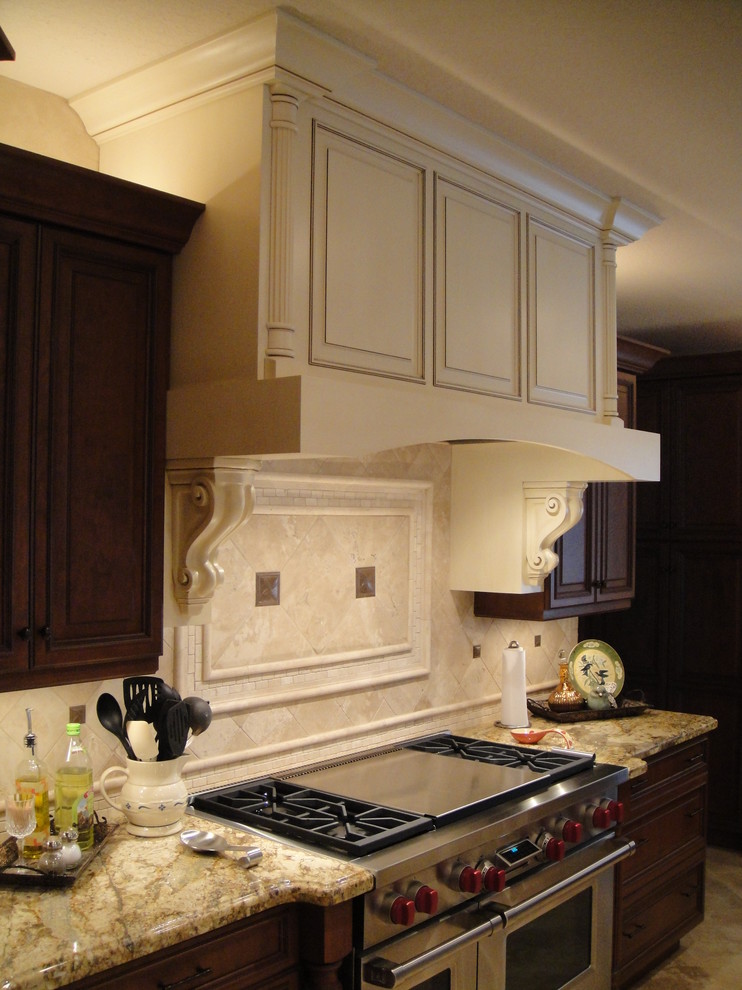 This is an example of a medium sized traditional u-shaped kitchen pantry in Houston with dark wood cabinets, granite worktops, stainless steel appliances and an island.