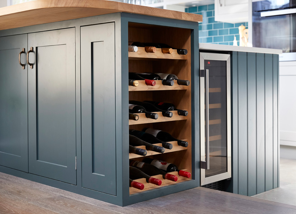 Mittelgroße Moderne Küche mit Schrankfronten im Shaker-Stil, blauen Schränken, Arbeitsplatte aus Holz, dunklem Holzboden, Kücheninsel und braunem Boden in London