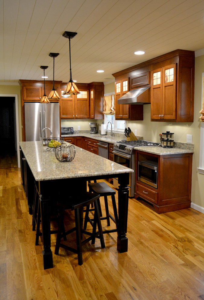 Example of a mid-sized classic l-shaped medium tone wood floor eat-in kitchen design in Charlotte with a double-bowl sink, flat-panel cabinets, medium tone wood cabinets, granite countertops, stainless steel appliances and an island
