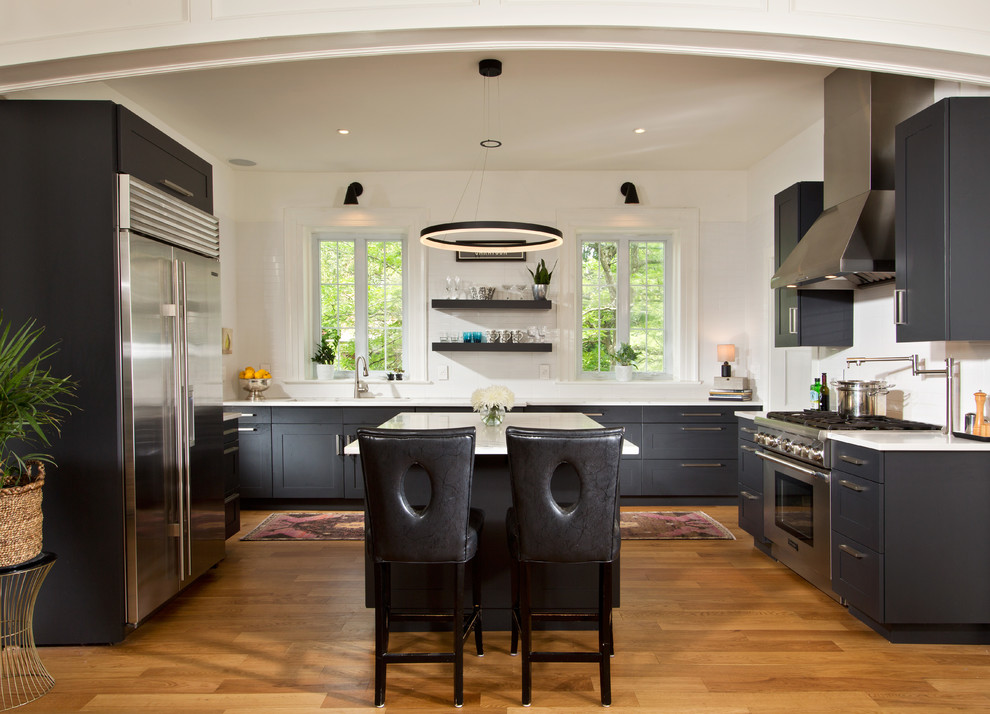 Cette image montre une grande cuisine américaine design en U avec un placard à porte shaker, des portes de placard bleues et îlot.