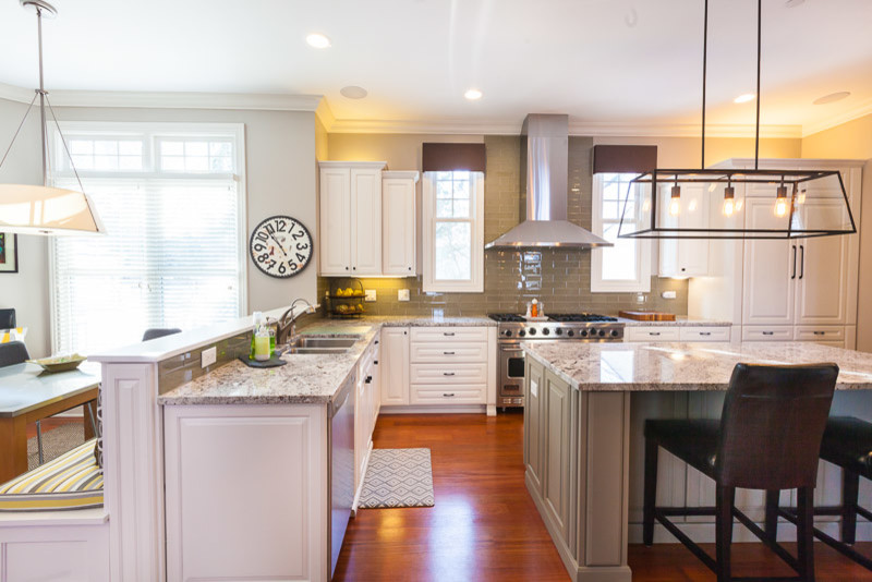 Exempel på ett stort modernt kök, med en undermonterad diskho, luckor med upphöjd panel, vita skåp, granitbänkskiva, grönt stänkskydd, stänkskydd i glaskakel, rostfria vitvaror, mellanmörkt trägolv och en köksö