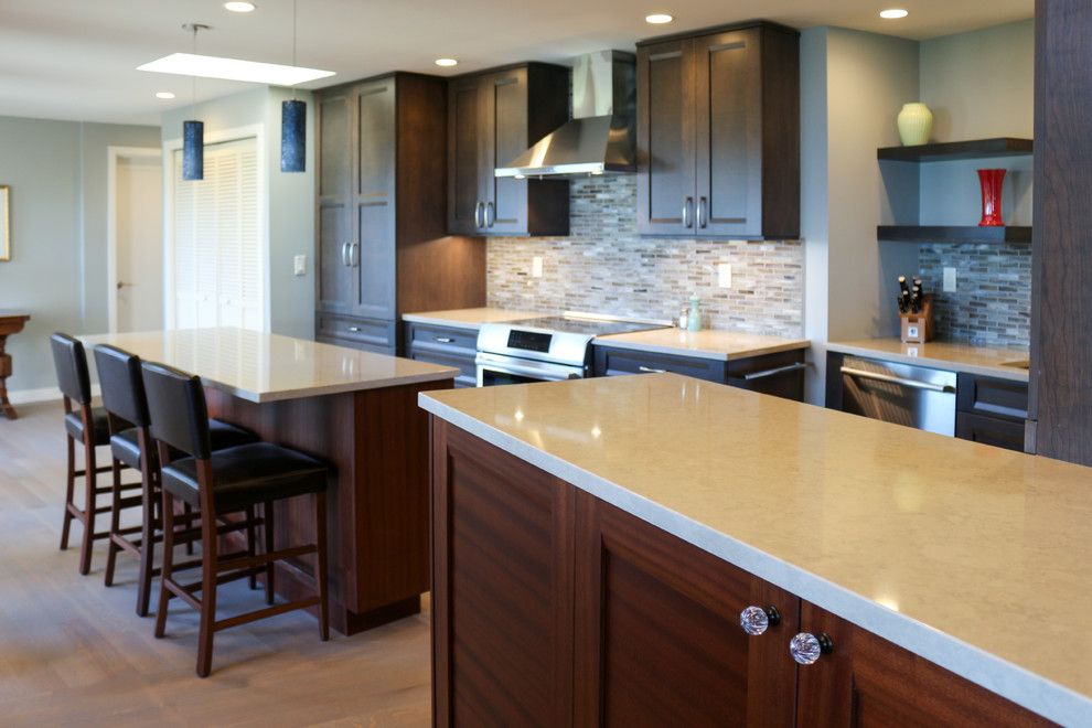 This is an example of a medium sized traditional galley kitchen/diner in Seattle with recessed-panel cabinets, engineered stone countertops, blue splashback, glass tiled splashback, stainless steel appliances, medium hardwood flooring, medium wood cabinets, a double-bowl sink, multiple islands, grey floors and blue worktops.