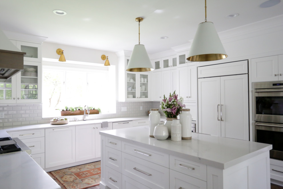 Inspiration for a large transitional u-shaped medium tone wood floor and brown floor eat-in kitchen remodel in Indianapolis with a farmhouse sink, recessed-panel cabinets, white cabinets, quartz countertops, white backsplash, subway tile backsplash, paneled appliances, an island and white countertops