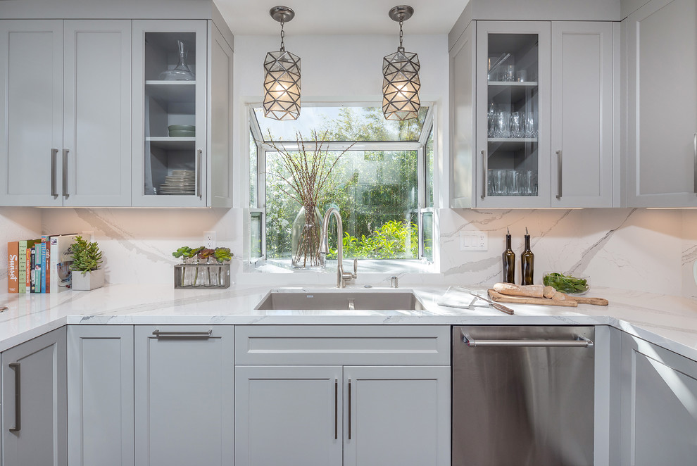 Photo of a medium sized modern kitchen/diner in San Francisco with a submerged sink, white cabinets, engineered stone countertops, white splashback, glass tiled splashback, stainless steel appliances, medium hardwood flooring, no island, brown floors and white worktops.