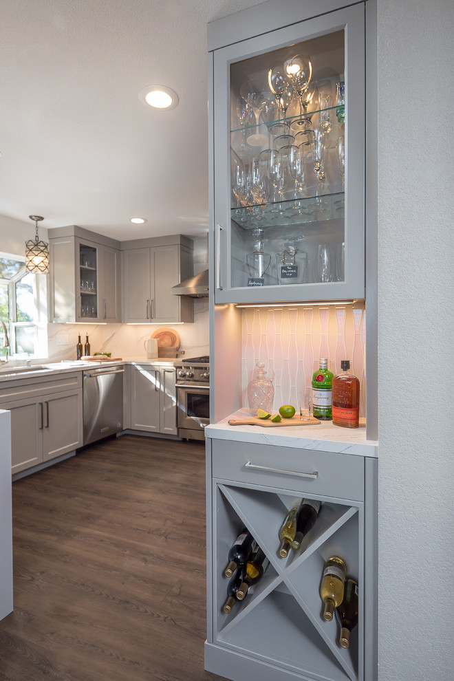 Photo of a medium sized modern kitchen/diner in San Francisco with a submerged sink, white cabinets, engineered stone countertops, white splashback, glass tiled splashback, stainless steel appliances, medium hardwood flooring, no island, brown floors and white worktops.
