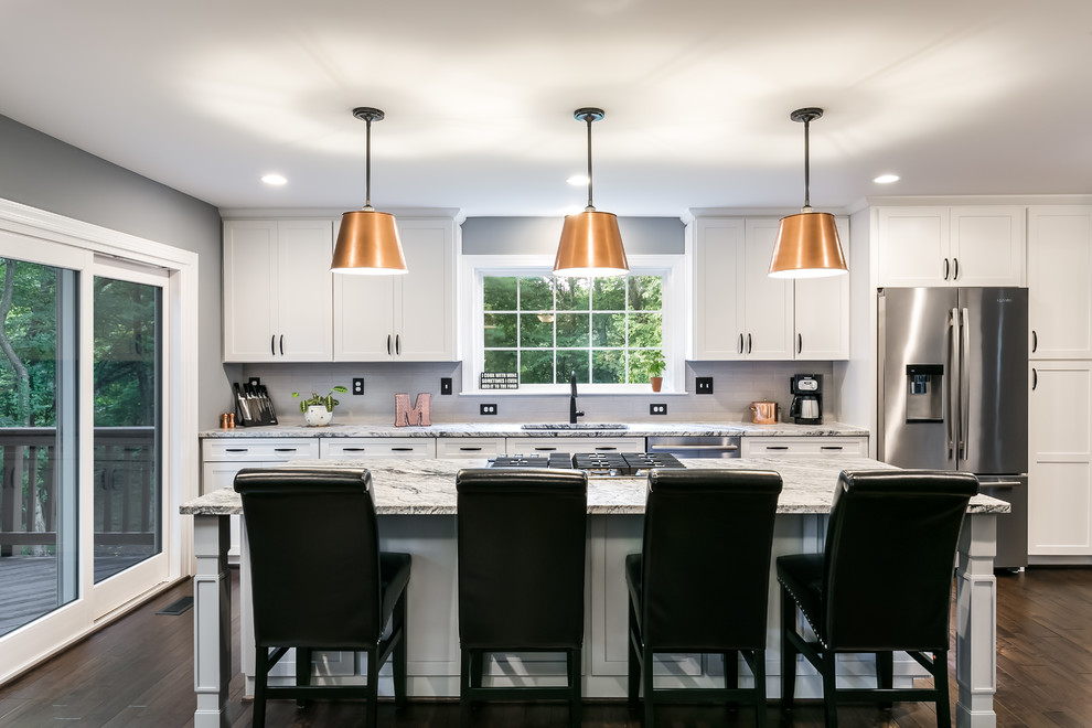 Inspiration for a mid-sized transitional galley brown floor and dark wood floor open concept kitchen remodel in DC Metro with an undermount sink, shaker cabinets, white cabinets, granite countertops, gray backsplash, porcelain backsplash, stainless steel appliances and an island