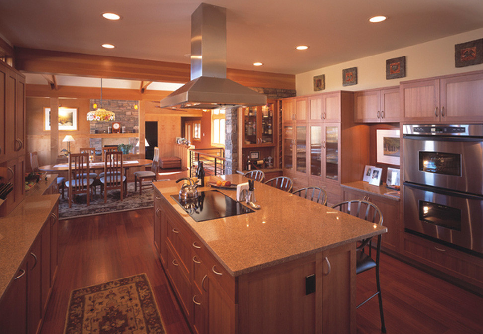 Immagine di una cucina design di medie dimensioni con ante con bugna sagomata, ante in legno scuro, top in granito, elettrodomestici in acciaio inossidabile e pavimento in legno massello medio