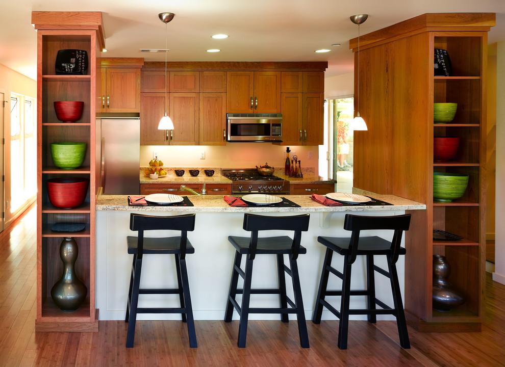 Inredning av ett modernt mellanstort kök, med skåp i mellenmörkt trä, granitbänkskiva, rostfria vitvaror, bambugolv, en undermonterad diskho, skåp i shakerstil, stänkskydd i sten och en köksö
