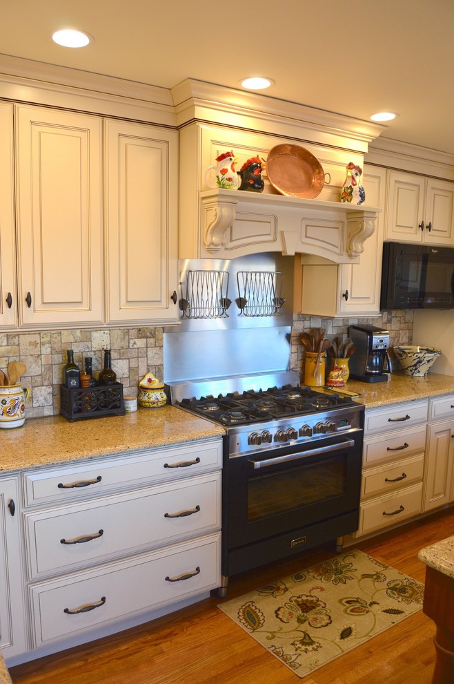 Enclosed kitchen - large traditional l-shaped light wood floor enclosed kitchen idea in DC Metro with a double-bowl sink, raised-panel cabinets, white cabinets, granite countertops, beige backsplash, stone tile backsplash, black appliances and an island