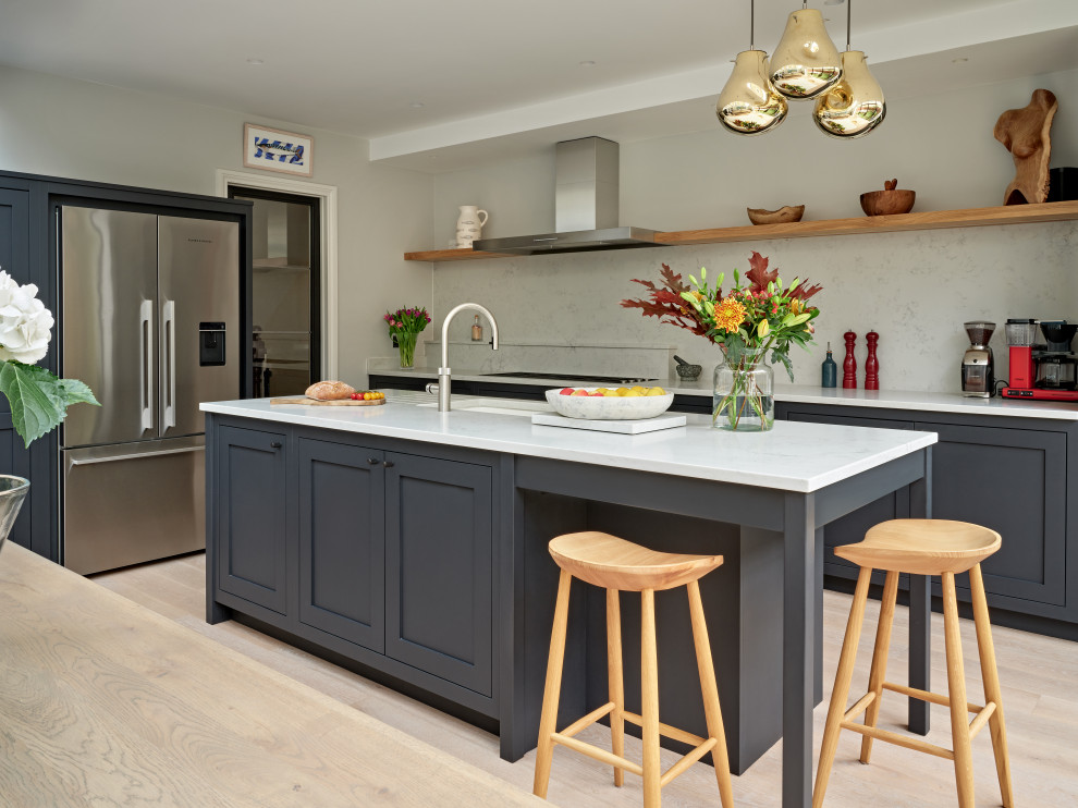 Example of a large transitional single-wall eat-in kitchen design in London with an undermount sink, shaker cabinets, black cabinets, quartzite countertops, white backsplash, quartz backsplash, stainless steel appliances, an island and white countertops