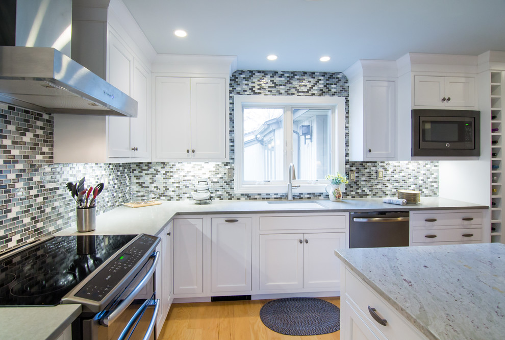 Large transitional l-shaped medium tone wood floor and brown floor eat-in kitchen photo in Philadelphia with an undermount sink, beaded inset cabinets, white cabinets, quartz countertops, multicolored backsplash, glass tile backsplash, stainless steel appliances, an island and gray countertops